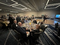 a group of people sitting at tables in a conference room