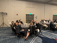 a group of people sitting at tables in a conference room